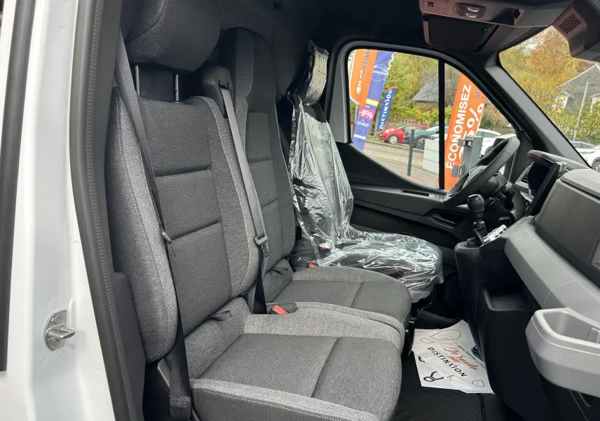 Vue intérieure côté gauche du Renault Master blanc 2026, montrant les sièges gris et le volant avec plastique de protection.