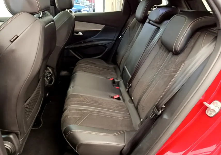 Vue latérale droite de l'intérieur arrière du Peugeot 3008 rouge, avec sièges en cuir et tissu noir.