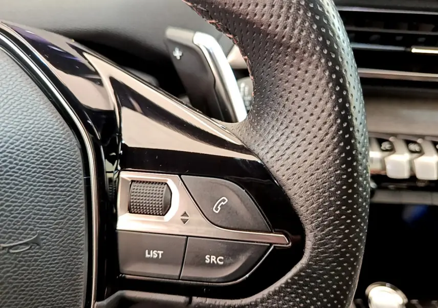 Gros plan sur les commandes gauche du volant cuir perforé du Peugeot 3008 GT rouge, avec touches appel et volume.