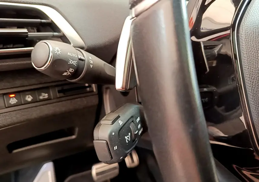 Gros plan sur la colonne de direction et commandes au volant du Peugeot 3008 GT 2021, intérieur noir.