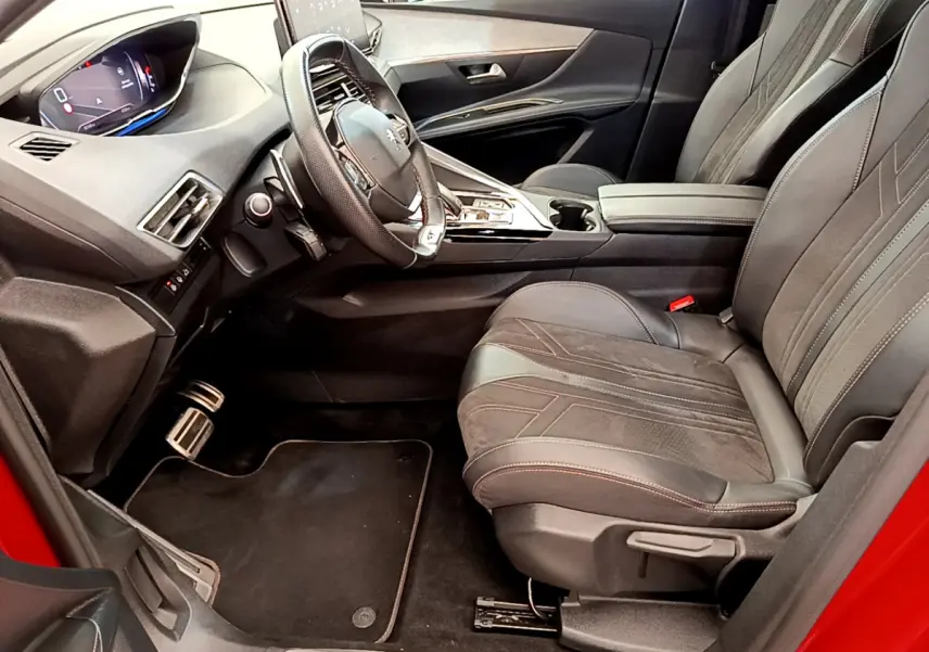 Intérieur côté conducteur du Peugeot 3008 GT rouge, avec tableau de bord numérique et sièges cuir noirs détaillés.