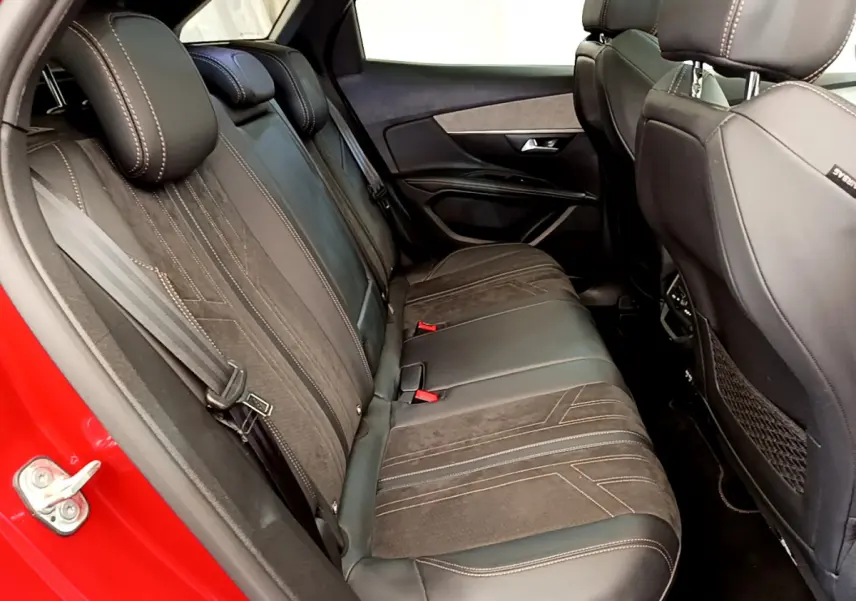 Vue intérieure côté gauche sur la banquette arrière en cuir noir du Peugeot 3008 rouge, avec surpiqûres contrastantes.