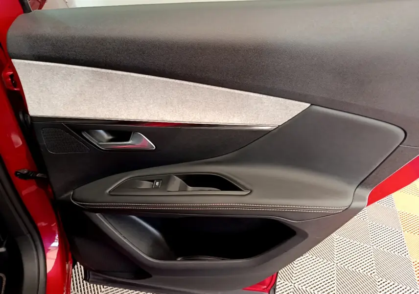 Gros plan sur la porte intérieure côté gauche rouge du Peugeot 3008 GT avec garniture noire et grise.