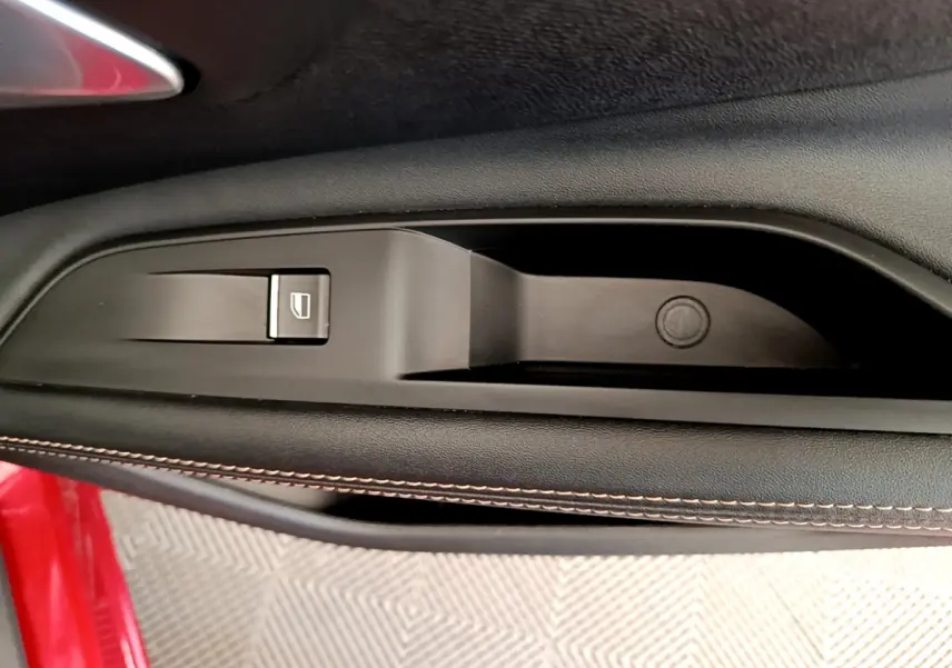Détail de la commande de lève-vitre sur la porte côté gauche d’un Peugeot 3008 rouge 2021.