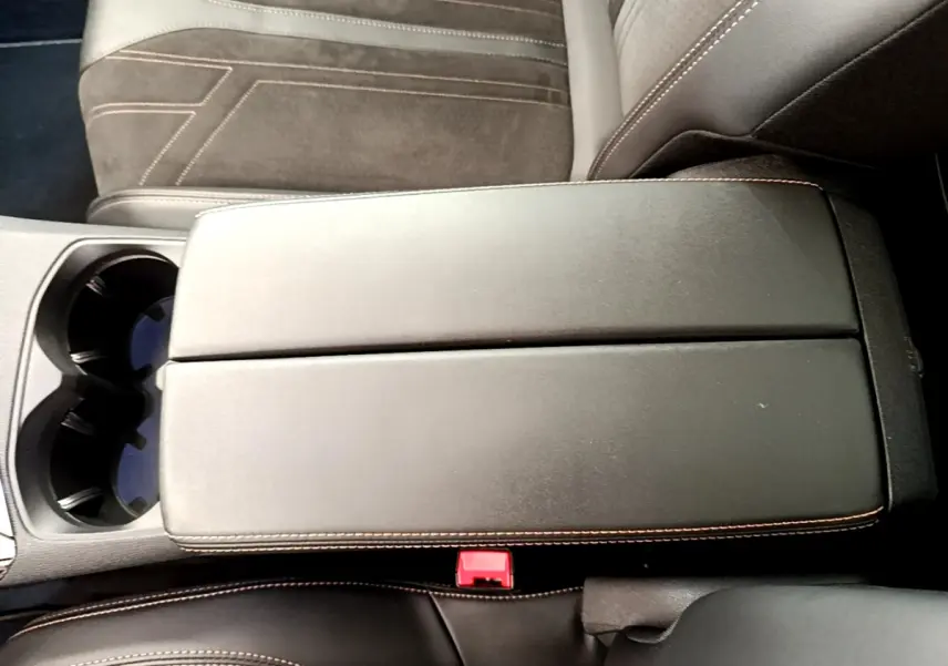 Accoudoir central noir avec surpiqûres orange, porte-gobelets et sièges en tissu gris du Peugeot 3008 GT 2021.