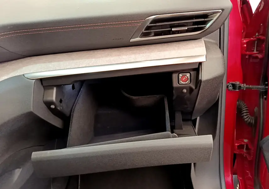 Intérieur du Peugeot 3008 GT 2021 rouge, vue côté passager avec boîte à gants ouverte et tableau de bord noir.