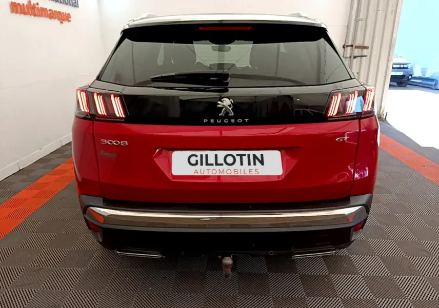 Vue arrière d'un Peugeot 3008 GT rouge avec feux LED distinctifs et attelage visible en intérieur showroom.