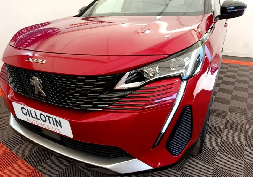 Vue 3/4 avant droit d'un Peugeot 3008 rouge avec calandre noire et feux LED distinctifs en forme de griffes.