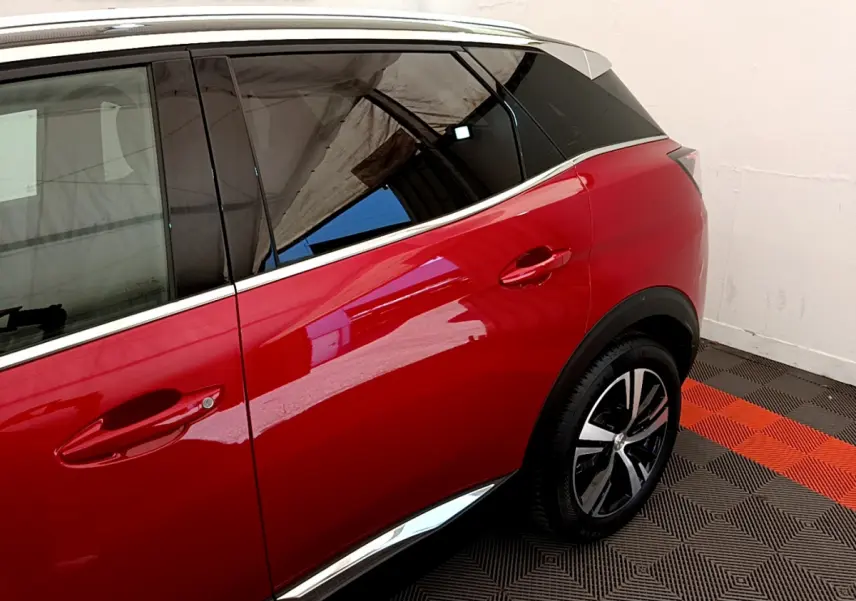 Vue côté droit arrière du Peugeot 3008 GT rouge avec jante alliage et vitrage teinté dans un garage.