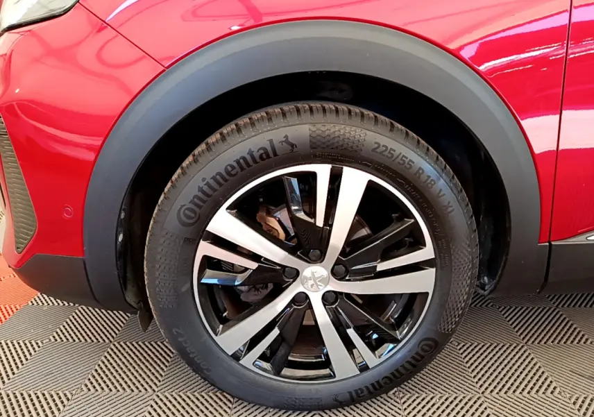 Gros plan sur la roue avant gauche rouge du Peugeot 3008 GT avec jante alliage bicolore et pneu Continental.