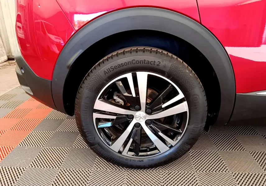 Gros plan sur la roue arrière droite d’un Peugeot 3008 rouge, avec jante alliage bicolore et pneu Continental.