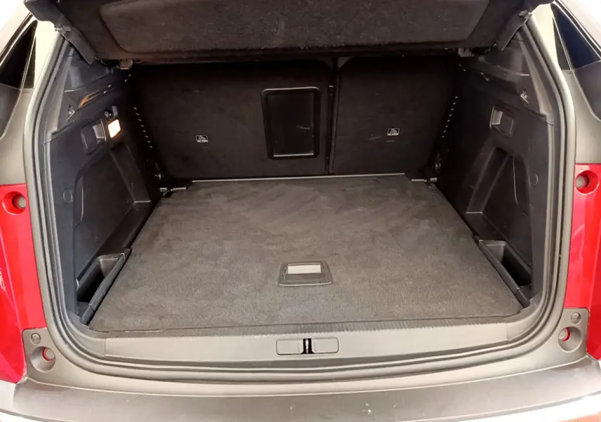 Coffre ouvert d'un Peugeot 3008 rouge, vue arrière montrant un espace de chargement spacieux et tapis noir.