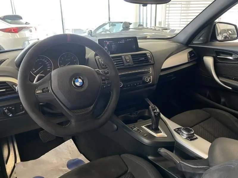 Vue intérieure côté conducteur de la BMW Série 1 135i 320CV 2013 avec volant multifonction et console centrale moderne.
