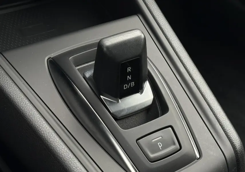 Gros plan sur la commande de boîte automatique noire du Renault Captur hybride, entourée de plastique gris et noir.