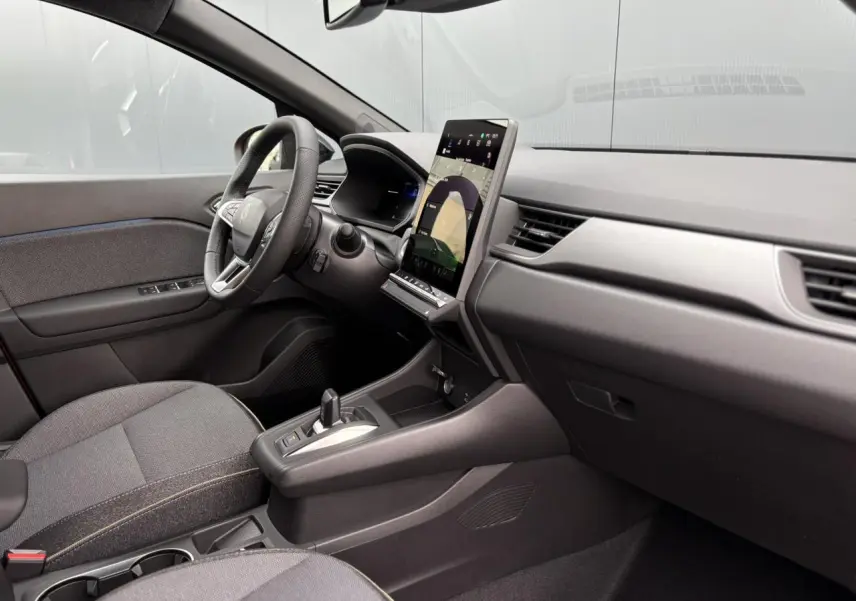 Vue intérieure côté conducteur du Renault Captur 2026, tableau de bord moderne avec écran tactile vertical et sièges tissu gris.