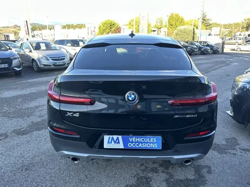 Vue arrière d'un BMW X4 X Drive 190 CV X-Line gris foncé, avec feux allongés et double sortie d'échappement.
