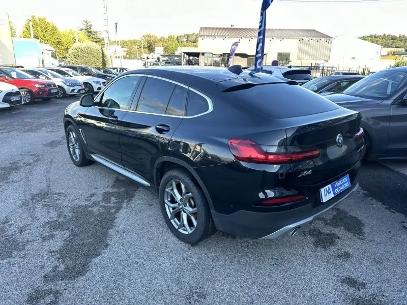BMW X4 X Drive 190 CV X-Line gris foncé vue 3/4 arrière droit sur parking avec détails chromés et vitres teintées.