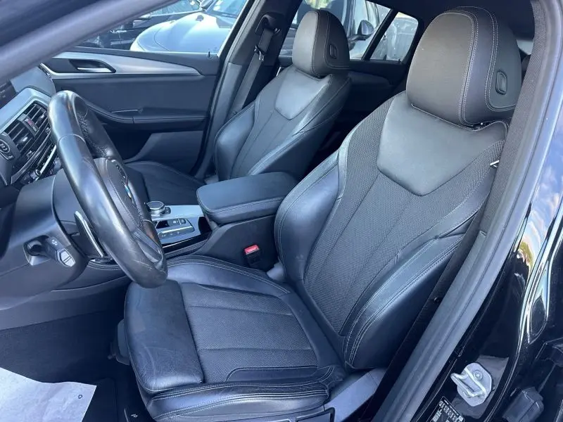 Intérieur du BMW X4 X-Line 2019, vue côté gauche sur les sièges en cuir noir et le tableau de bord moderne.