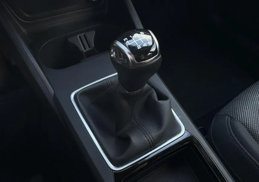 Gros plan sur le levier de vitesses manuel noir de l'Audi Q2 30 TDI 116 S-Line, avec coutures apparentes.