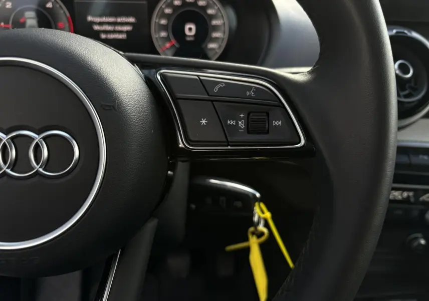 Gros plan sur le volant cuir multifonction de l'Audi Q2 30 TDI S-Line 2025 avec commandes audio et téléphone.