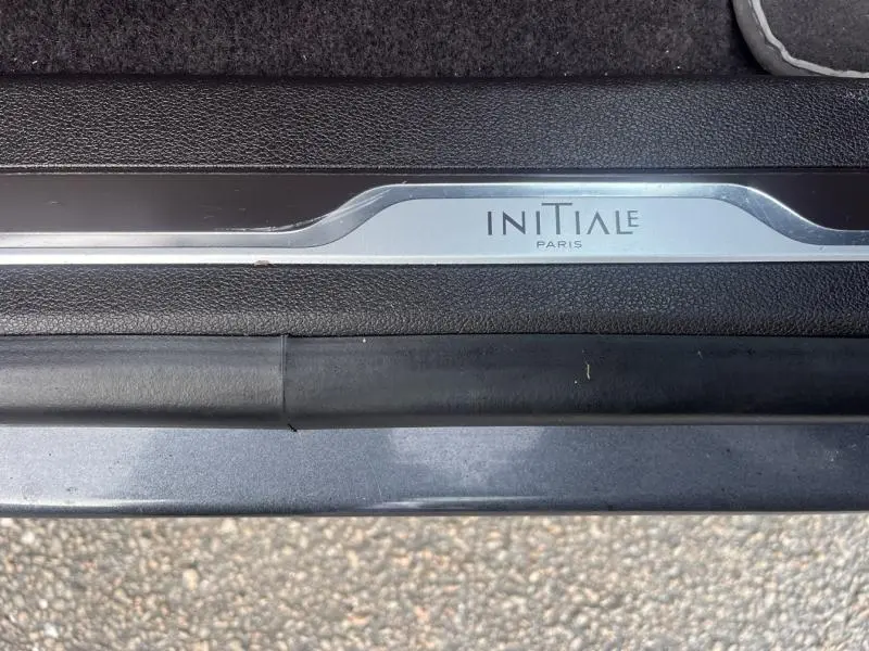 Gros plan sur la plaque de seuil de porte "Initiale Paris" du Renault Espace gris Cassiopée, intérieur cuir noir.