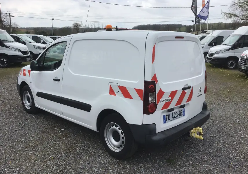 Vue 3/4 arrière droite d'un Citroën Berlingo blanc utilitaire avec bandes rouges réfléchissantes et attelage jaune.