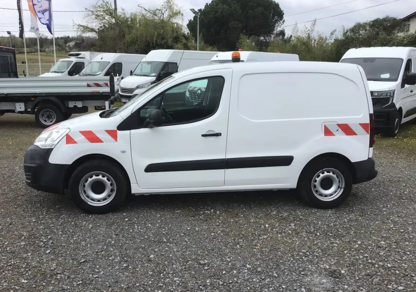 Vue de profil côté gauche d’un utilitaire Citroën Berlingo blanc de 2019 avec bandes rouges réfléchissantes et gyrophare orange.