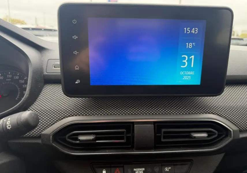Vue rapprochée de l'écran tactile central et des aérateurs du tableau de bord de la Dacia Sandero blanche 2021.