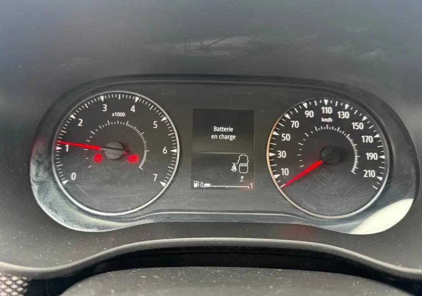 Vue rapprochée du tableau de bord de la Dacia Sandero blanc, affichant le compte-tours, la vitesse et un message "Batterie en charge".