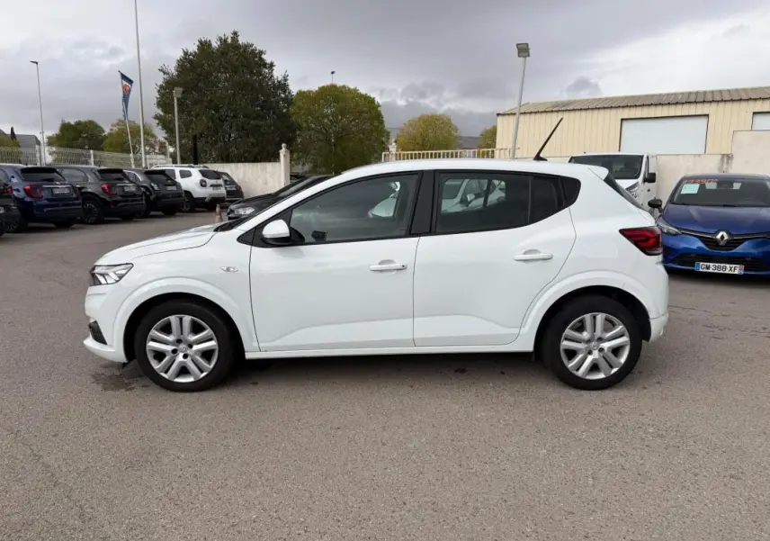 Profil côté gauche d'une Dacia Sandero blanche 2021, avec vitres surteintées et jantes alliage visibles.