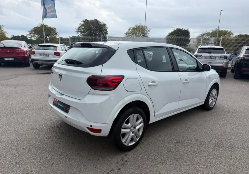 Vue 3/4 arrière droite d'une Dacia Sandero blanche 2021, avec feux arrière distinctifs et vitres surteintées.