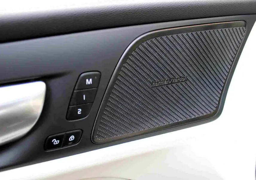 Gros plan sur la porte côté conducteur du Volvo S60 gris métal 2024, mettant en valeur l'enceinte Harman Kardon et les commandes mémoire.