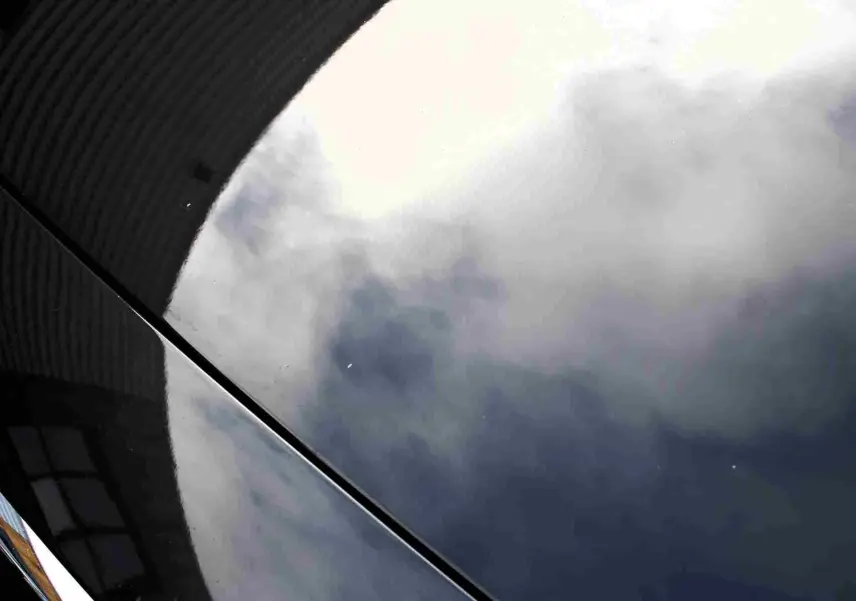 Reflet nuageux sur la carrosserie gris métal d'une Volvo S60 T6 AWD 2024 vue en gros plan côté droit.