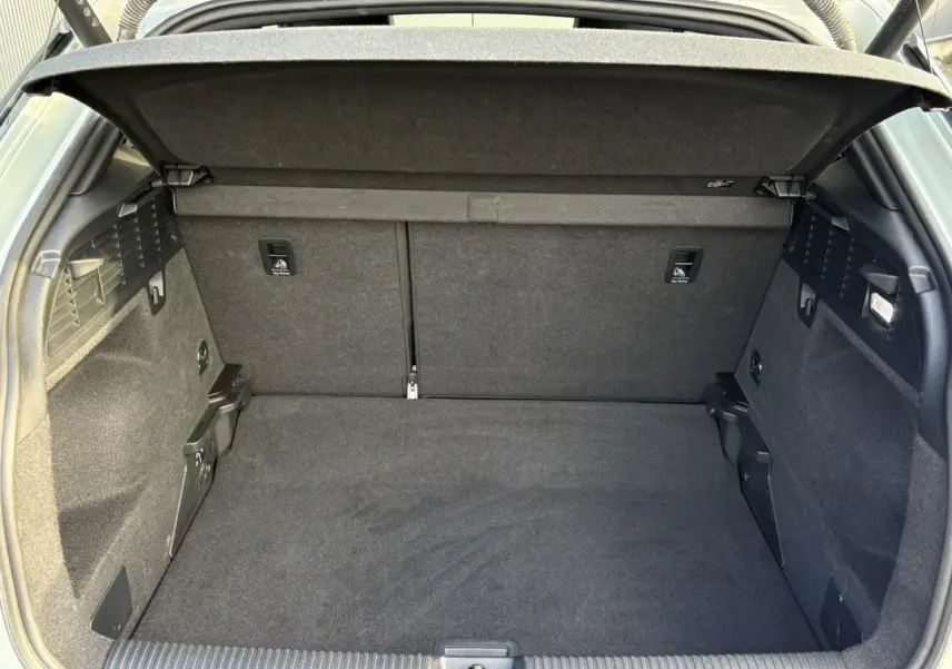 Coffre ouvert vu de l'arrière d'un Audi Q2 35 TDI S-Line 2025, intérieur tissu noir spacieux et propre.