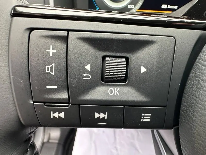 Gros plan sur les commandes multifonctions noires au volant du Nissan Qashqai Hybrid e-POWER blanc nacré 2025.