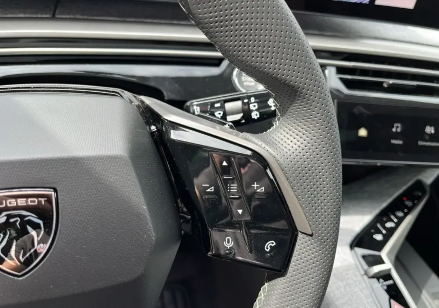 Gros plan sur le volant cuir perforé du Peugeot 5008 Hybrid 145 GT Alcantara avec commandes multifonctions.