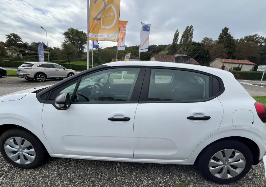 Profil côté gauche d'une Citroën C3 blanche 5 portes de 2017, avec poignées et rétroviseur noirs, sur un parking extérieur.