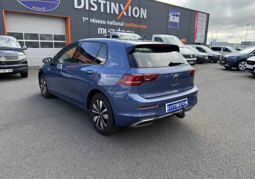 Vue 3/4 arrière droite d'une Volkswagen Golf 8 bleue anémone métallisée avec attelage escamotable et vitres surteintées.