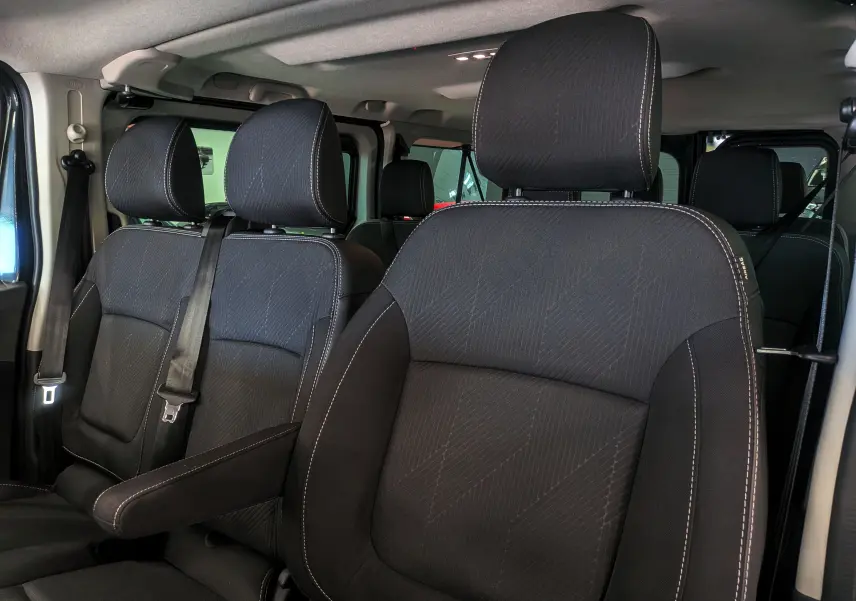 Vue intérieure rapprochée des sièges avant en tissu noir avec surpiqûres blanches du Renault Trafic Combi 2025.