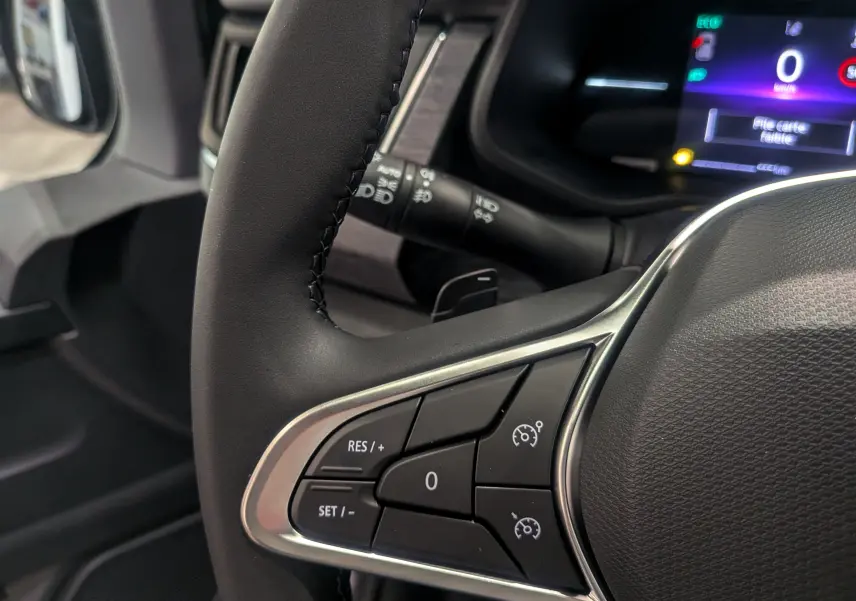 Gros plan sur le volant côté gauche du Renault Trafic Combi 2025, avec commandes de régulateur de vitesse et tableau de bord digital.