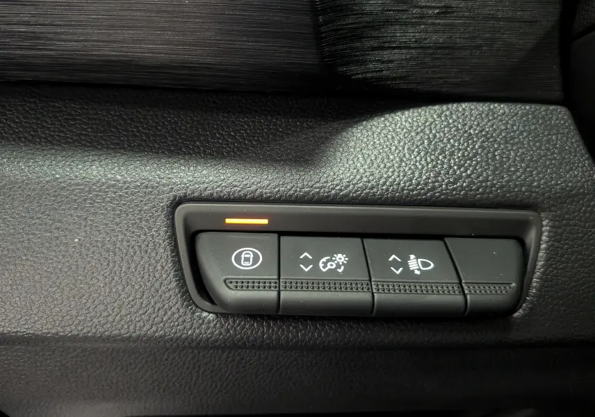 Gros plan sur les commandes de réglage des phares et du tableau de bord du Renault Trafic Combi gris Comète 2025.