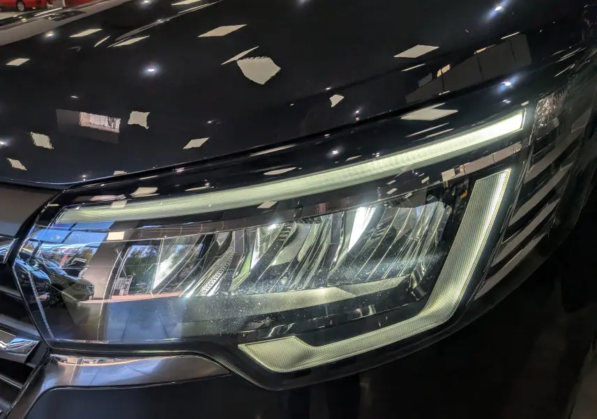 Gros plan sur le phare avant droit du Renault Trafic Combi gris comète, mettant en valeur son éclairage LED moderne.