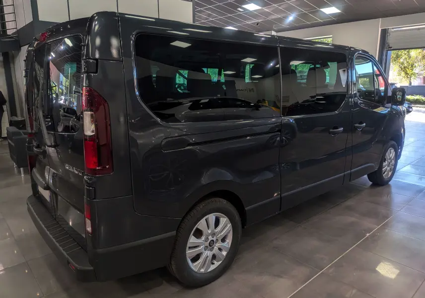 Renault Trafic Combi gris Comète vu en 3/4 arrière droit dans un showroom lumineux avec vitres teintées.
