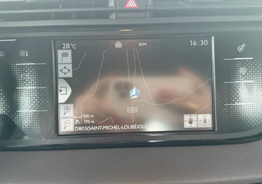 Vue rapprochée de l'écran de navigation du tableau de bord d'une Citroën C4 Picasso blanche, affichant la carte et la température.