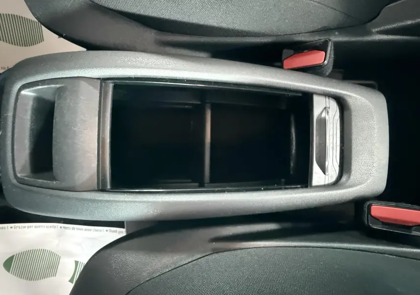 Vue plongeante sur le rangement central noir entre les sièges avant d'une Citroën C4 Picasso blanc 2014.