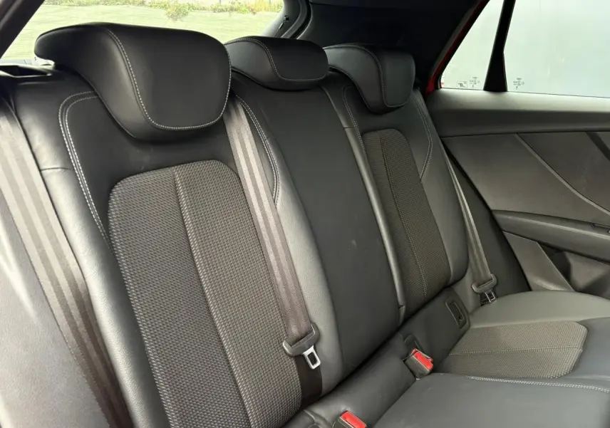 Vue intérieure du siège arrière droit en cuir et tissu noir de l'Audi Q2 35 TDI S-Line rouge 2025.