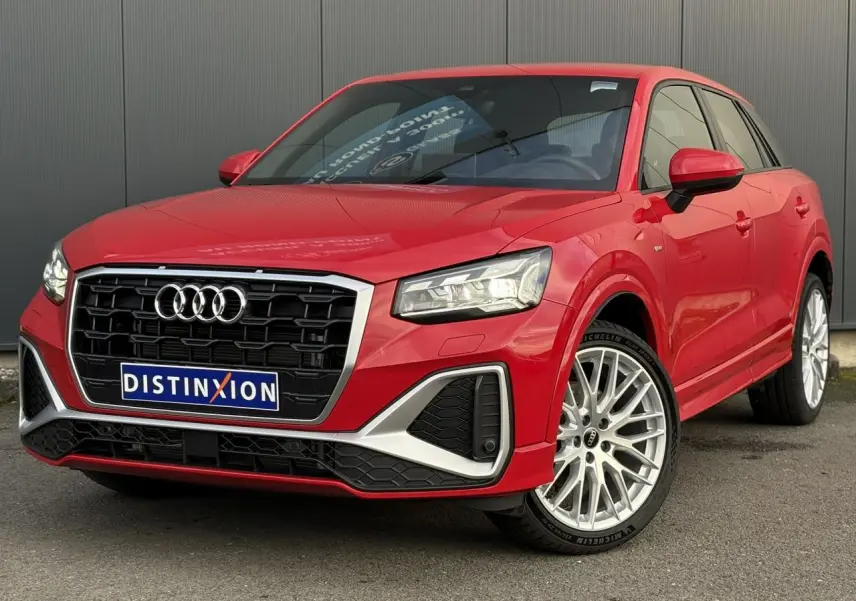 Audi Q2 35 TDI S-Line rouge vue 3/4 avant droit, avec calandre noire et jantes alliage multibranches.