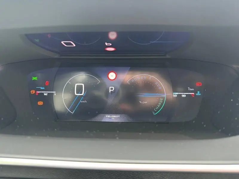 Tableau de bord numérique du Peugeot 2008 hybride gris 2025, affichant la vitesse à zéro et indicateurs de charge et puissance.
