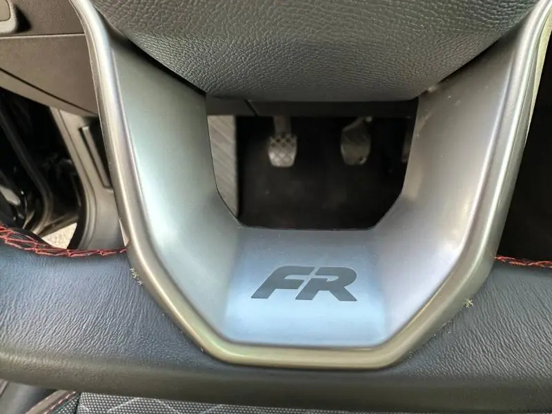 Gros plan sur le bas du volant avec logo FR et surpiqûres rouges, intérieur du SEAT LEON ST noir Minuit Métallisée.