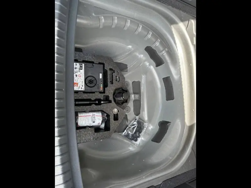 Vue en plongée sur le coffre d'un SEAT LEON ST 2025, montrant la roue de secours et les outils de bord.